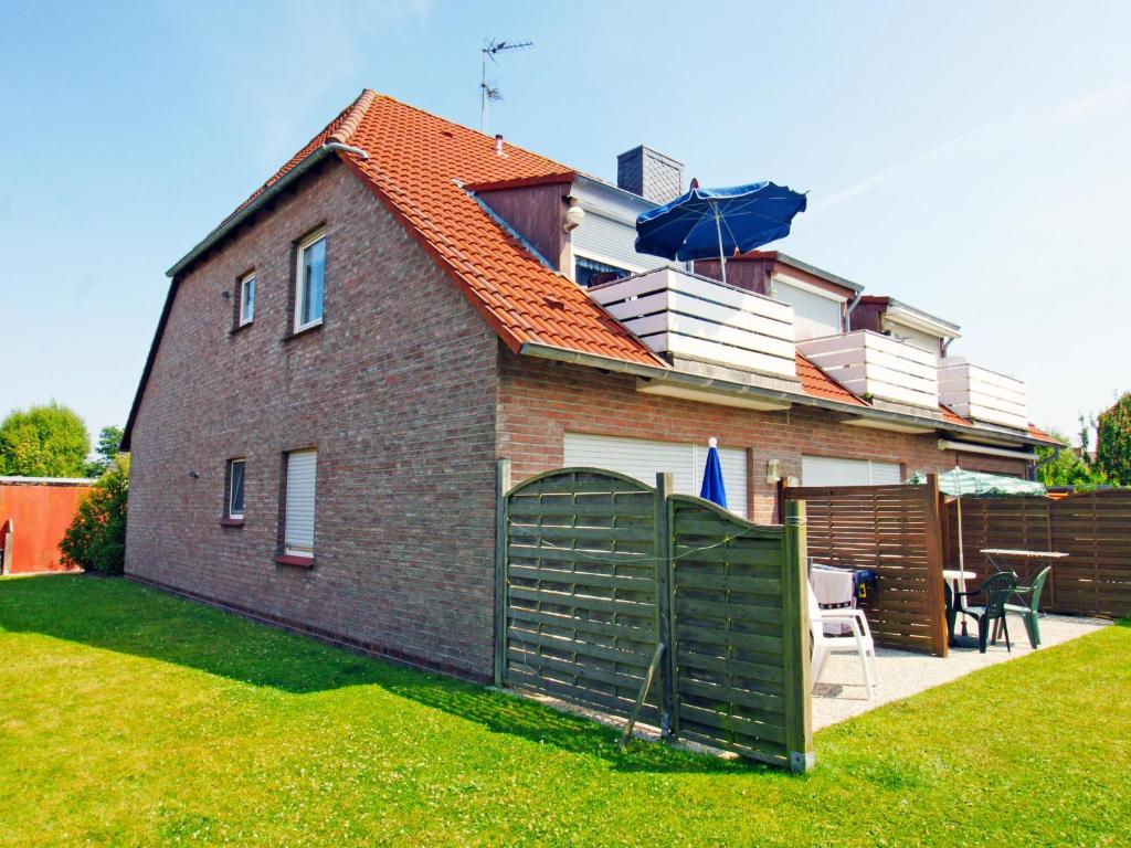 ein Backsteinhaus mit einem Zaun im Hof in der Unterkunft Apartment Kluntje by Interhome in Norddeich