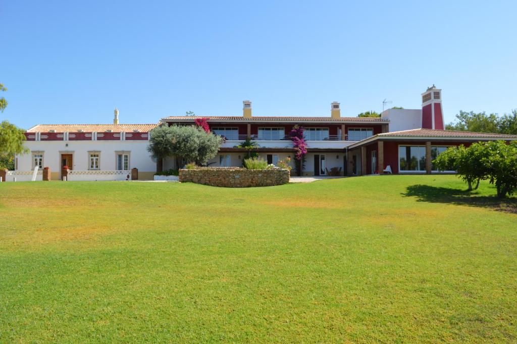 un bâtiment avec une grande pelouse devant lui dans l'établissement Quinta da Mesquita, à Pêra