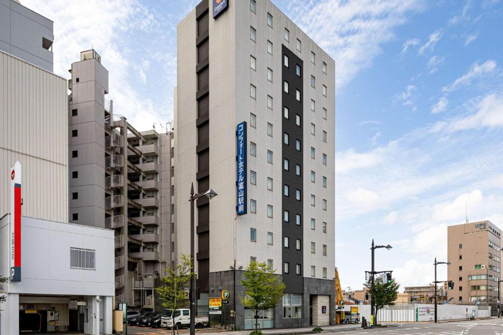 a tall white building with a blue sign on it at Comfort Hotel Toyama in Toyama
