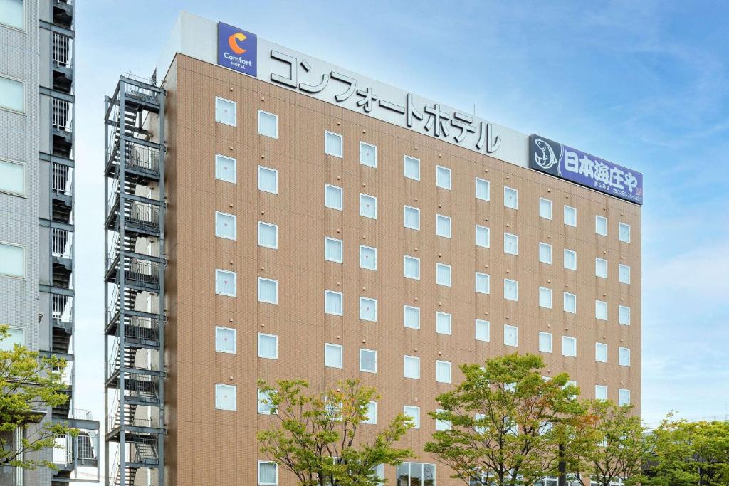 a building with a sign on the top of it at Comfort Hotel Tsubamesanjo in Sanjo