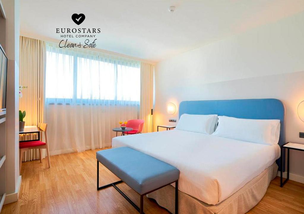 sypialnia z dużym białym łóżkiem z niebieskim zagłówkiem w obiekcie Eurostars Málaga w Maladze