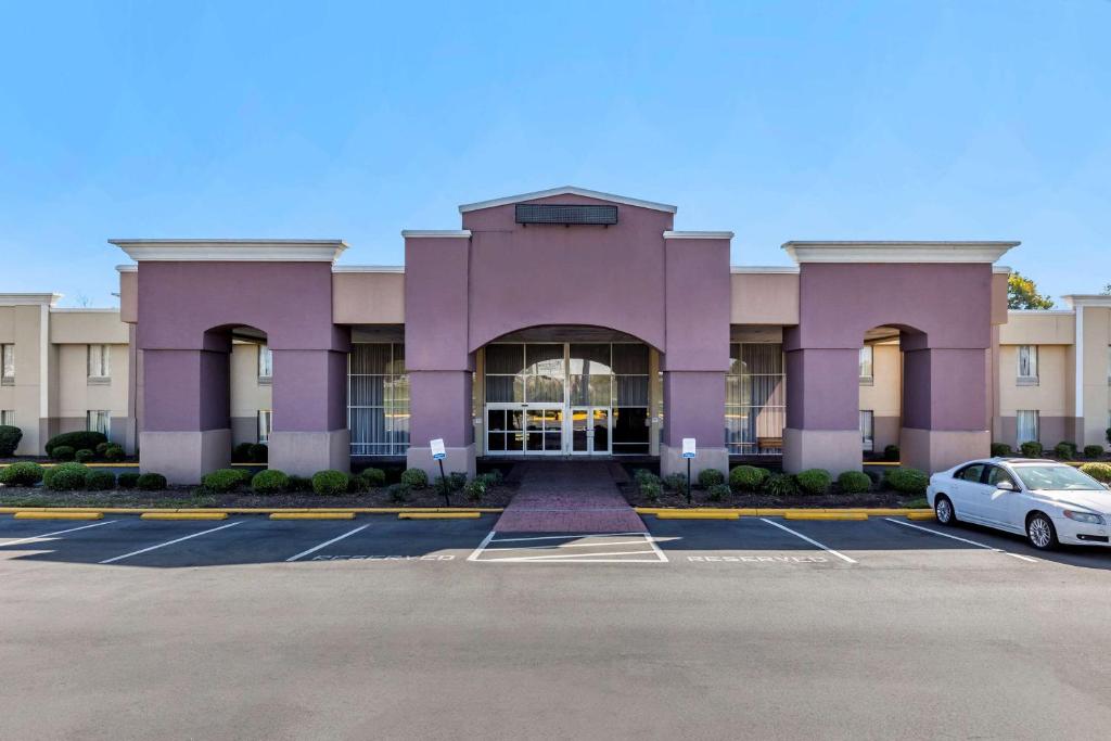 Quality Inn & Suites - Greensboro-High Point في جرينسبورو: مبنى ارجواني مع سيارة متوقفة في موقف للسيارات