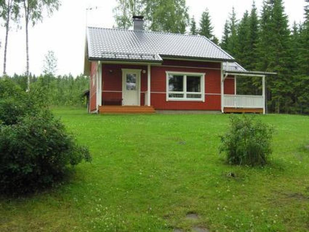 une maison rouge dans un champ d'herbe verte dans l'établissement Holiday Home Helmiranta by Interhome, à Saarijärvi