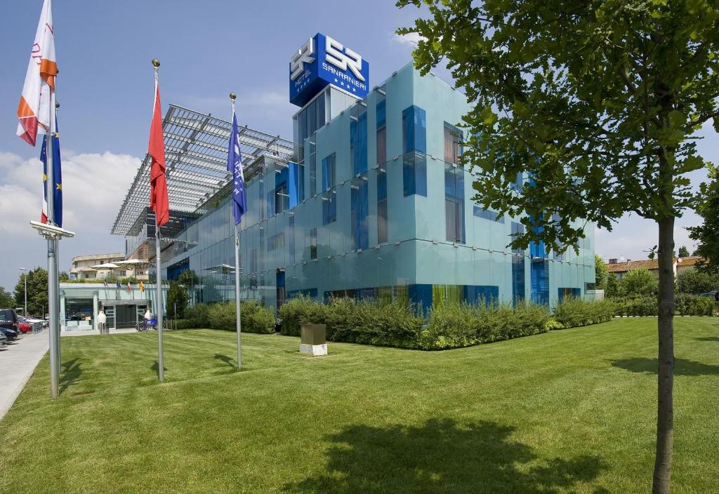 a building with flags in front of a park at San Ranieri Hotel in Pisa