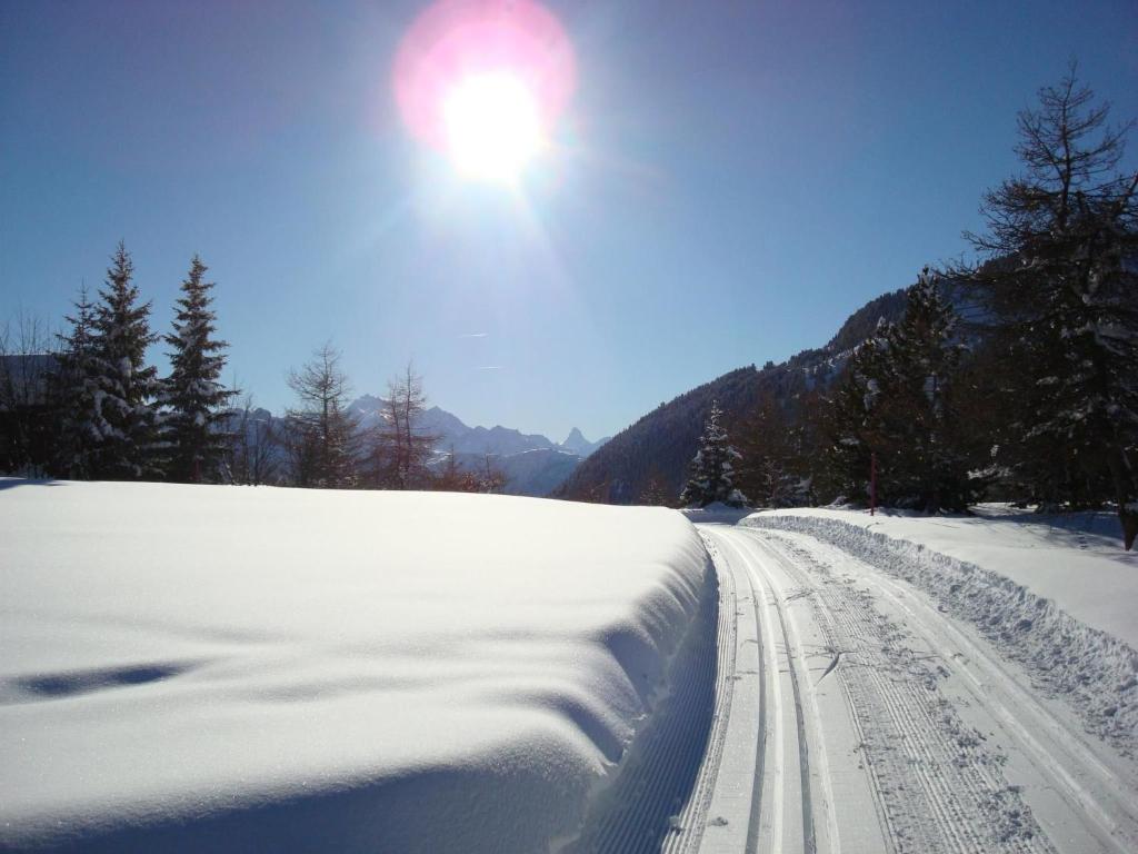 a snow covered road with the sun in the sky at Apartment Almenrausch Andreas by Interhome in Riederalp