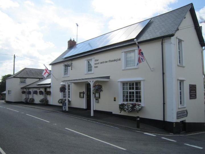 a white building with flags on the side of a street at The Rest and Be Thankful Inn in Minehead