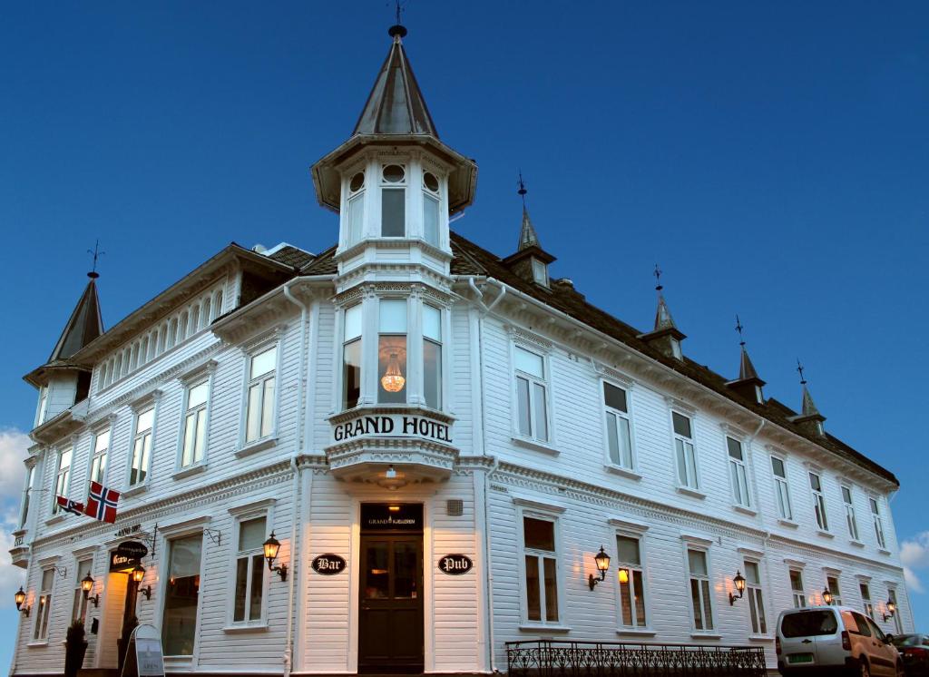 um grande edifício branco com uma torre de relógio no topo em Grand Hotel Flekkefjord em Flekkefjord