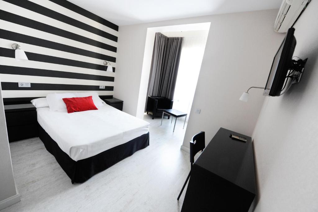 um quarto de hotel com uma cama com uma almofada vermelha em Hotel Domus em Málaga