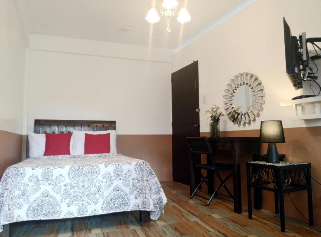 1 dormitorio con cama, escritorio y espejo en Jil's Apartelle, en Tagaytay