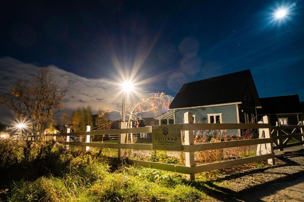 a house with a fence and a ferris wheel at night at SuliLand Domki pod Ślężą in Sulistrowice