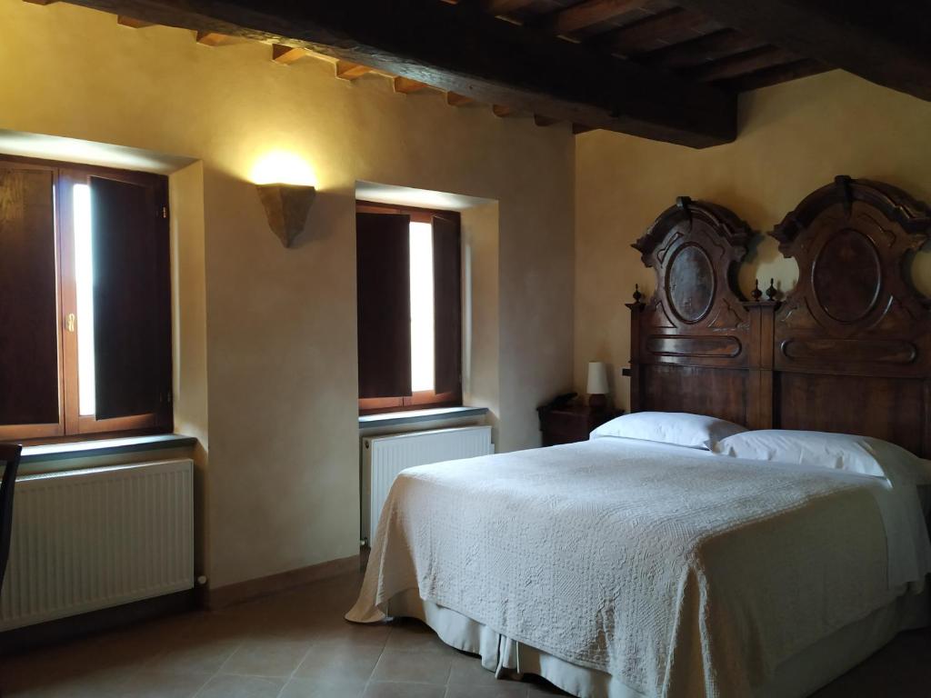 a bedroom with a large bed and two windows at Relais Monastero Di San Biagio in Nocera Umbra