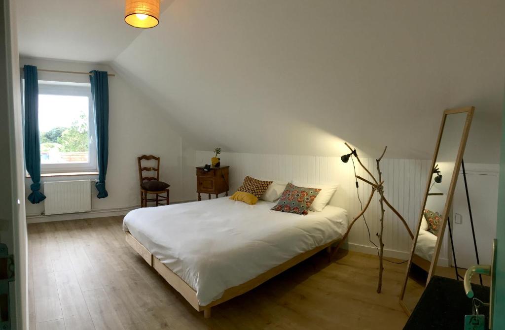 een slaapkamer met een wit bed en een spiegel bij Maison Glaz in Gâvres