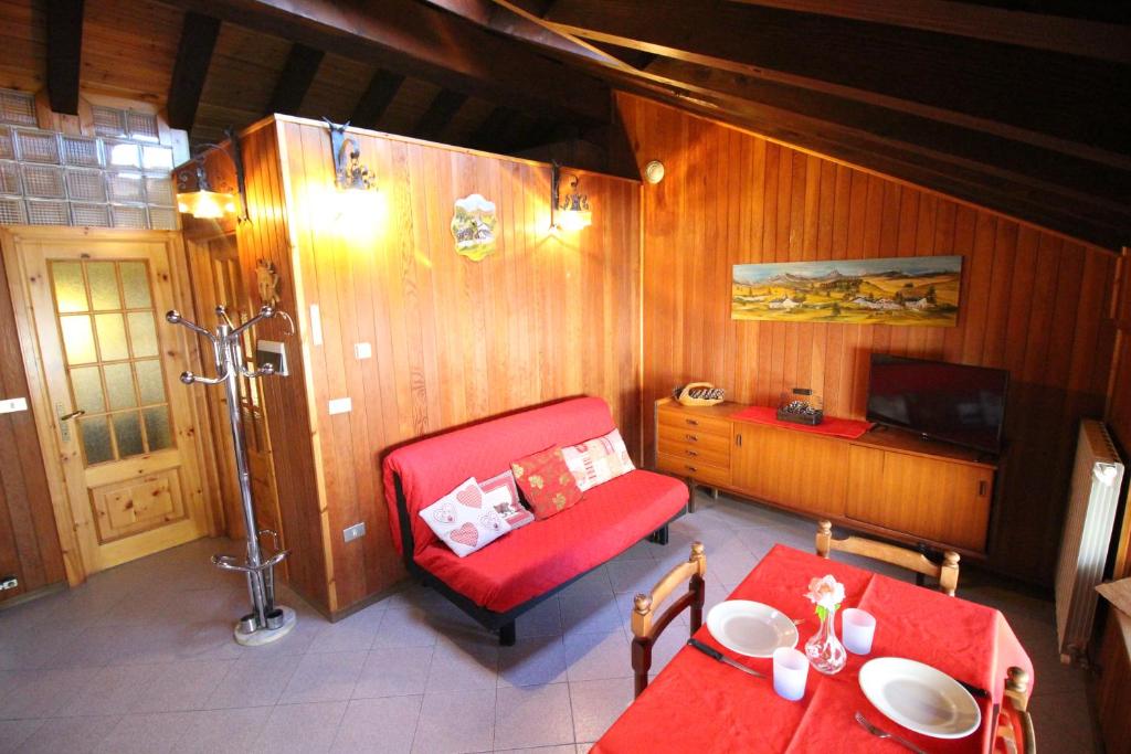 a living room with a red couch and a table at Appartamento Il Camoscio - Affitti Brevi Italia in Brusson