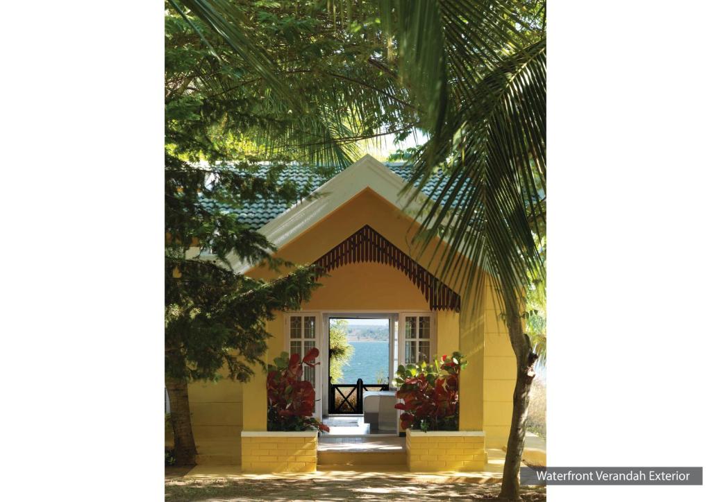 Begūr的住宿－士乃卡碧尼度假村，前方有棕榈树的黄色房子