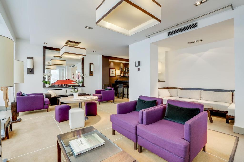 パリにあるHotel Duret Parisの紫色の椅子とソファ付きのリビングルーム