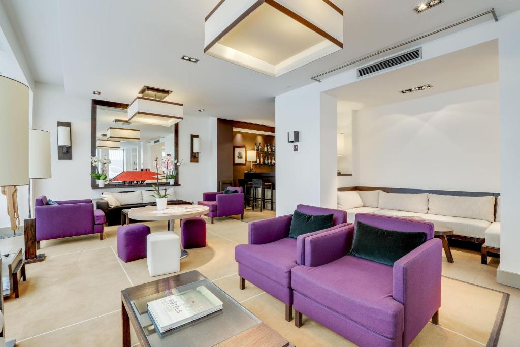 a living room with purple chairs and a couch at Hotel Duret Paris in Paris