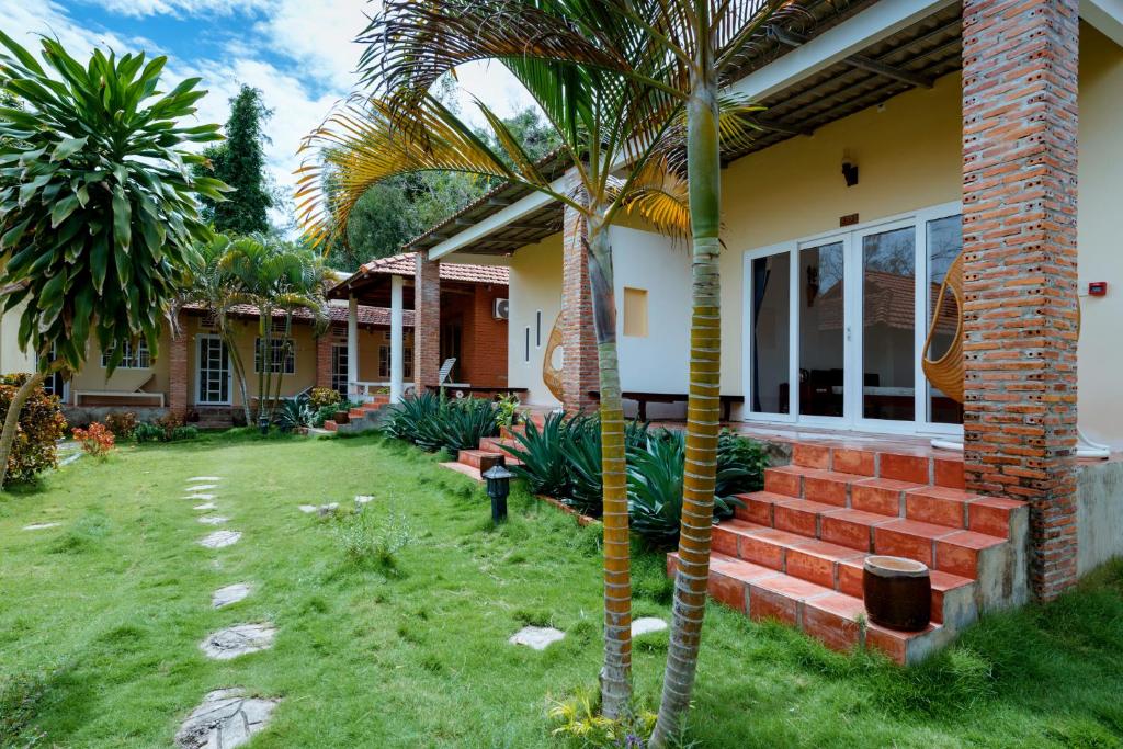 a house with a palm tree in the yard at Vung Bau Resort in Phú Quốc