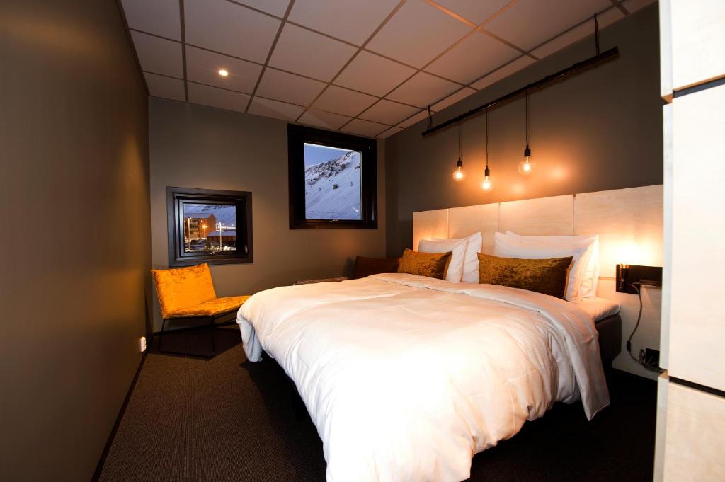 a bedroom with a large white bed and a window at Svalbard Hotell | The Vault in Longyearbyen