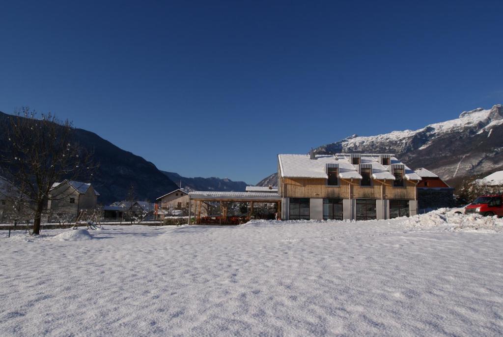 a large building in the snow with mountains in the background at Apartments Jojo in Bovec
