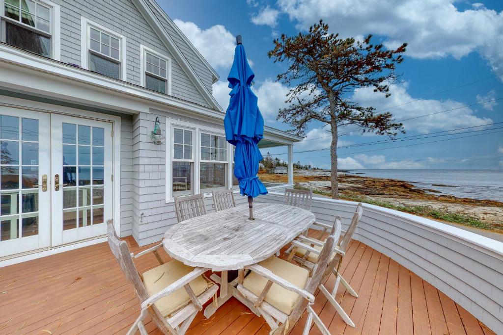 a table and chairs with an umbrella on a porch at Tranquil Ocean Retreat in Boothbay