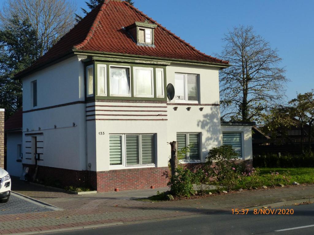 una casa blanca con techo rojo en una calle en Ferienwohnung Dianna, en Nordenham