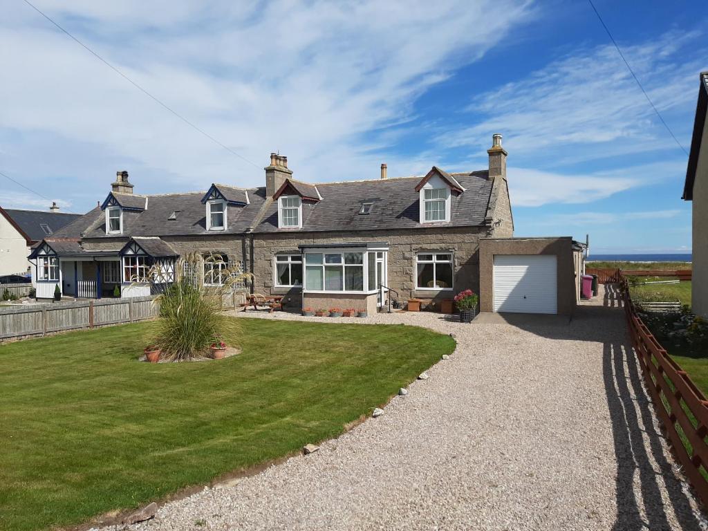 a large house with a yard and a fence at The Mouries Holiday Cottage in Fochabers