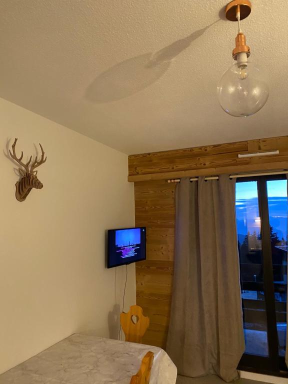 ein Wohnzimmer mit einem TV und einem Fenster in der Unterkunft Studio résidence les vans in Chamrousse