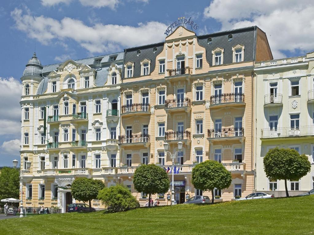 een groot wit gebouw met bomen ervoor bij Hotel Paris in Mariánské Lázně