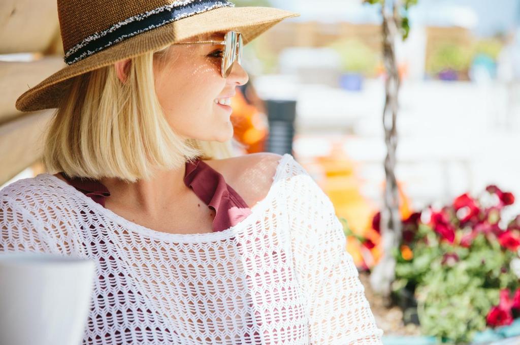 a woman wearing a straw hat sitting at a table at Hotel Indigo Orange Beach - Gulf Shores by IHG in Gulf Shores