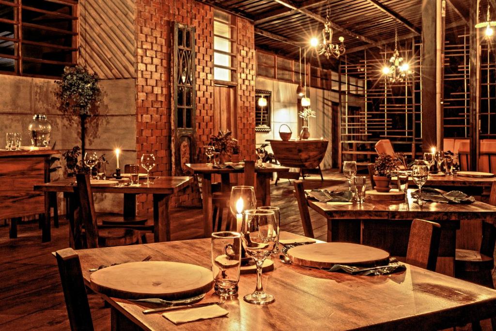 Archidona的住宿－Kuyana Amazon Lodge，餐厅设有木桌和椅子及灯