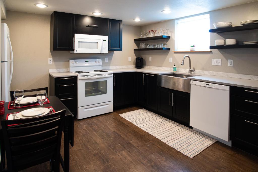 a kitchen with black cabinets and white appliances at The Lewis House in Laramie