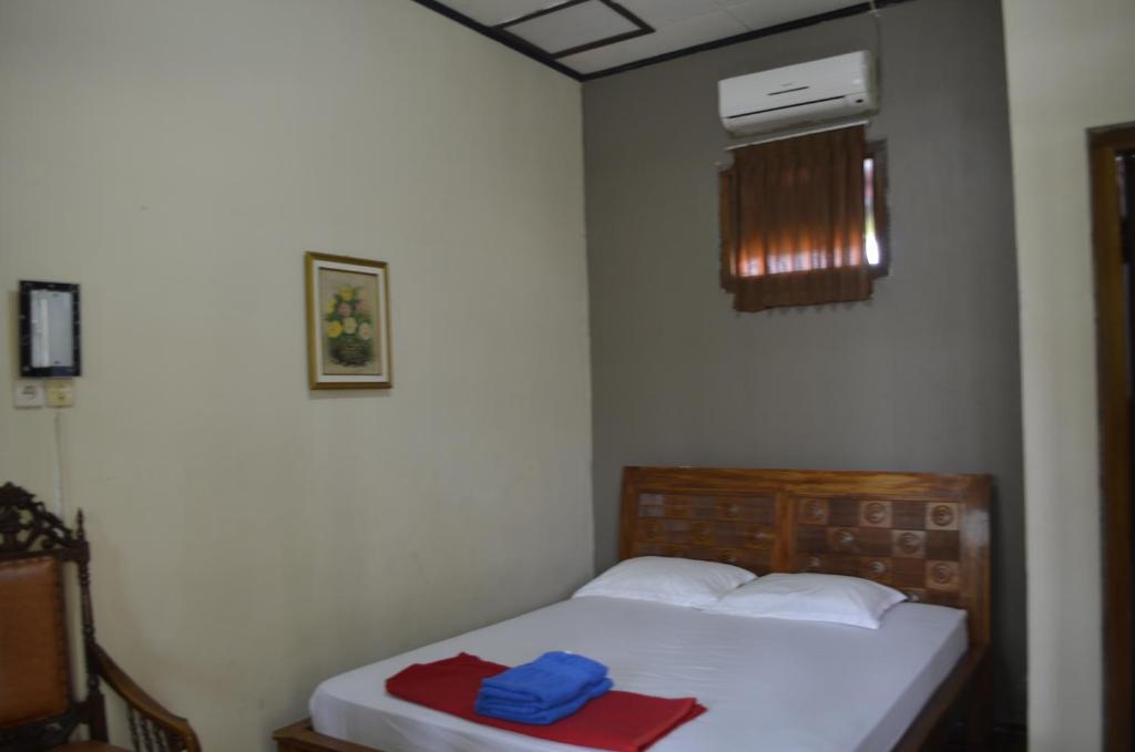 a small bedroom with a bed and a air conditioner at Sartika Hotel Prawirotaman in Yogyakarta