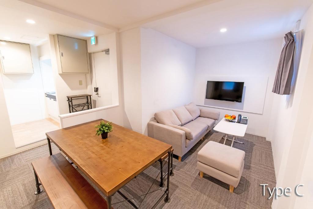 ein Wohnzimmer mit einem Tisch und einem Sofa in der Unterkunft Hermitage Nishi Shinjuku in Tokio