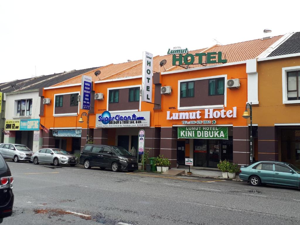 Lumut Hotel في لوموت: شارع فيه سيارات تقف امام الفندق