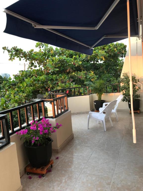 a patio with a blue umbrella and two chairs and flowers at HOSPEDAJE CARIBE EXPRESS in Cartagena de Indias