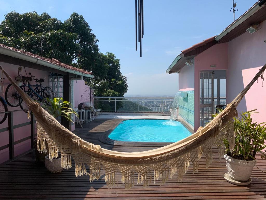 a hammock on the deck of a house with a pool at Casa Aurora Luz do Amanhecer in Rio de Janeiro