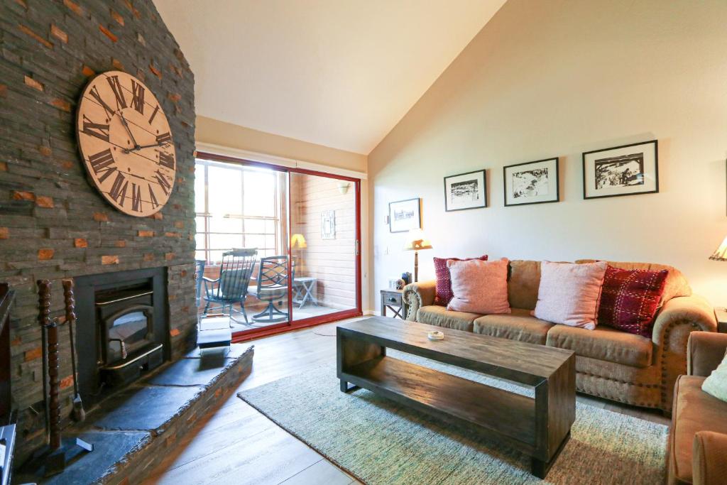 una sala de estar con un reloj grande sobre una chimenea de ladrillo en Aspen Creek #306 Condo, en Mammoth Lakes