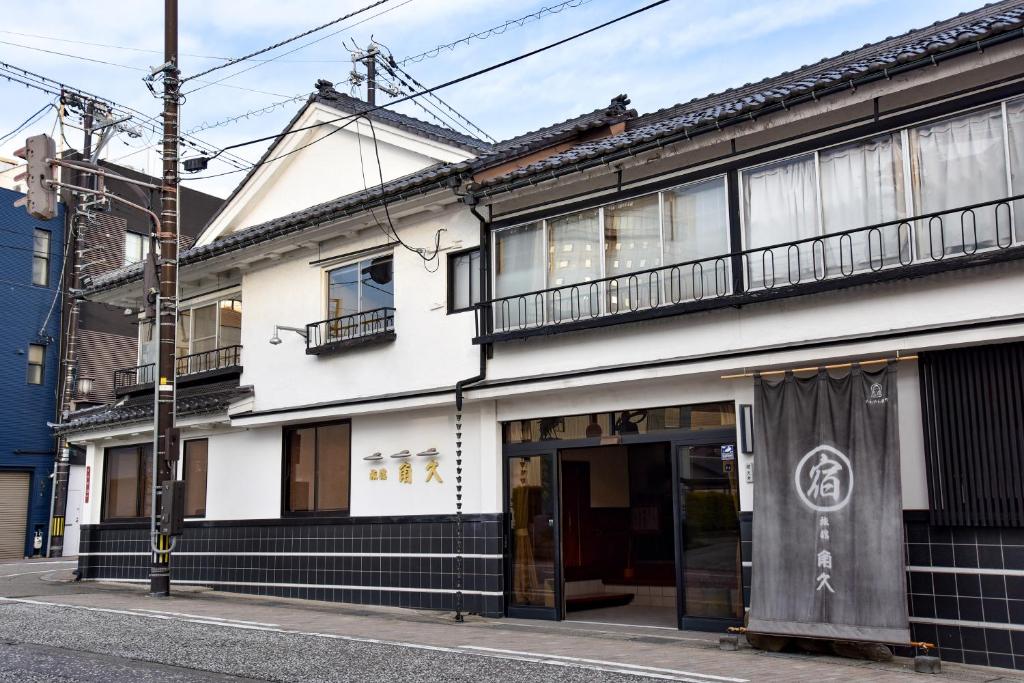 - un bâtiment blanc avec une façade noire et blanche dans l'établissement Kadokyu Ryokan, à Takaoka