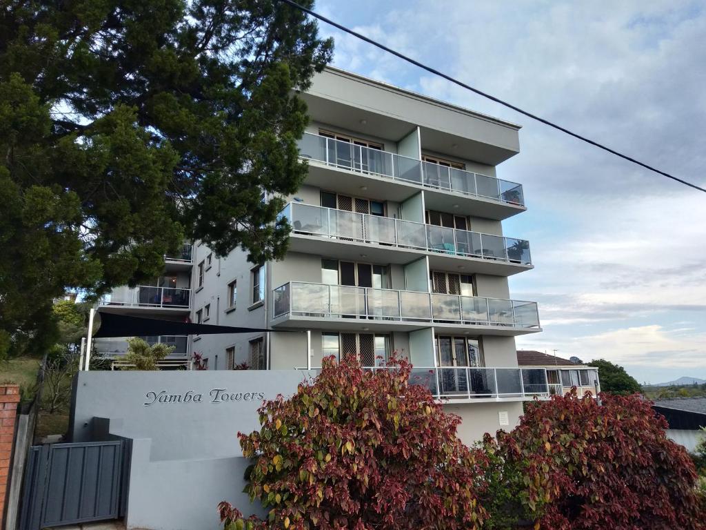 a white apartment building with a flowering bush in front of it at Yamba Towers 2 - LJHooker Yamba in Yamba