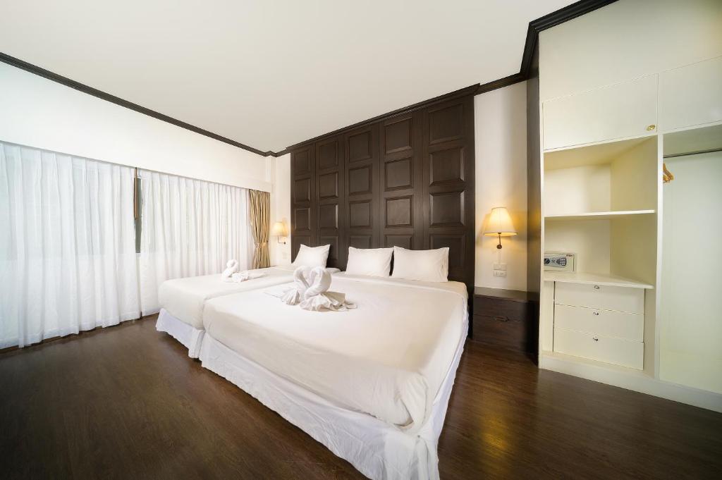 a bedroom with two beds with white sheets at The Wing Lanna Hotel in Chiang Mai