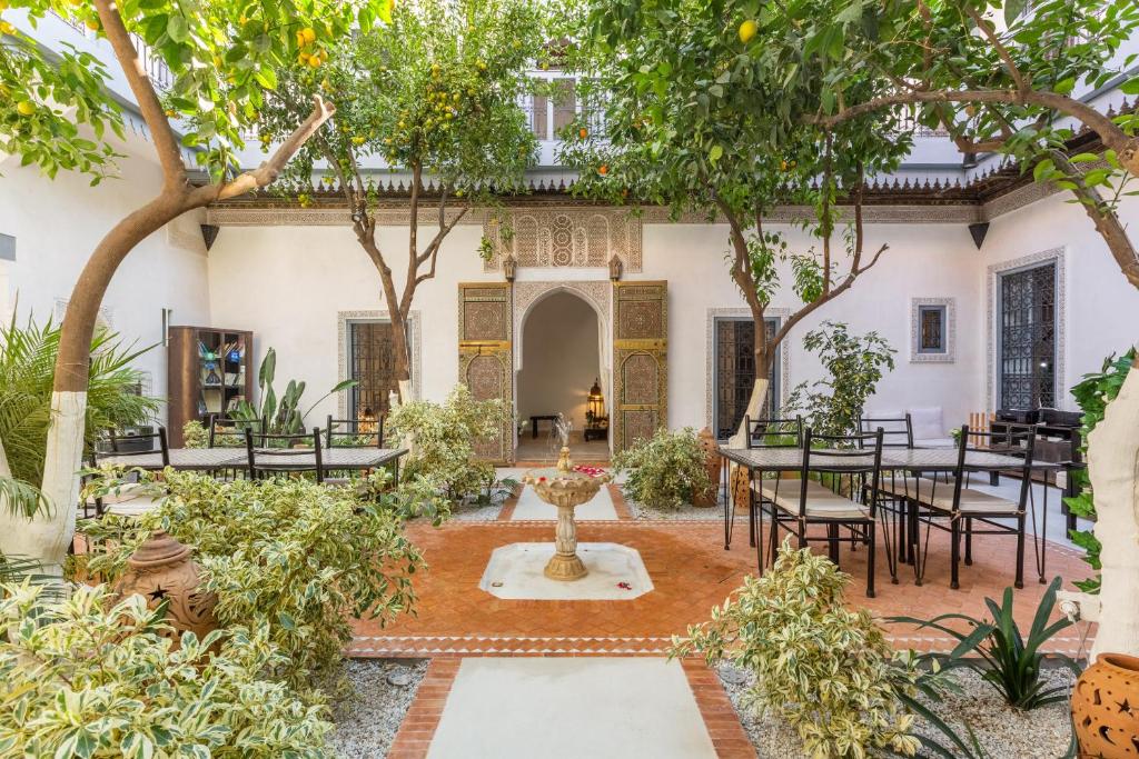 a courtyard with a fountain and tables and trees at Riad Tchaikana in Marrakech