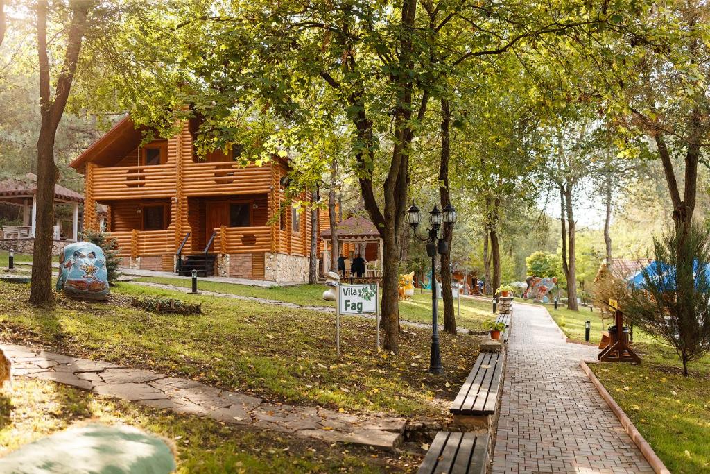 uma cabana de madeira num parque com um passeio e árvores em Sky Land Camping & Resort em Chişinău