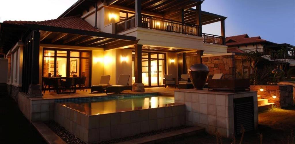 a house with a swimming pool in front of a house at Zimbali Heritage Place in Ballito