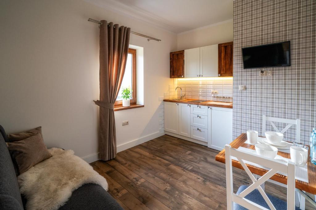 a living room with a table and a kitchen at Apartamenty "Góralskie Kąty" agroturystyka in Szaflary