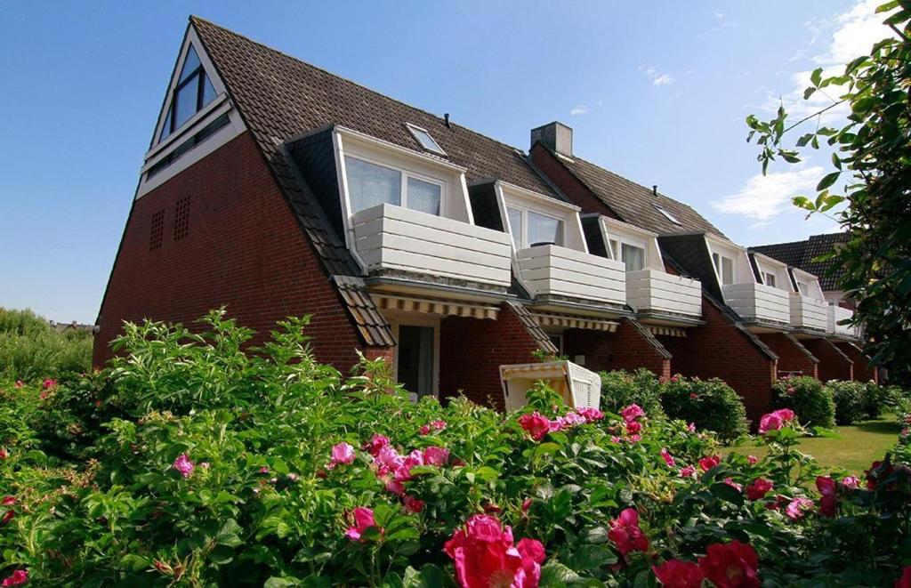 ein rotes Backsteinhaus mit weißen Fenstern und Blumen in der Unterkunft Wohnung Sylter Brise in Wenningstedt-Braderup