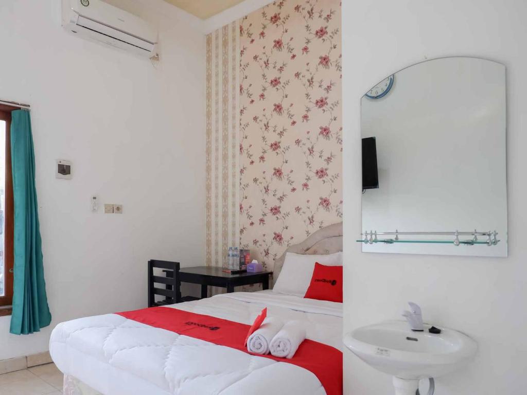 um quarto com uma cama, um lavatório e um espelho em RedDoorz near RSUD Nganjuk em Nganjuk