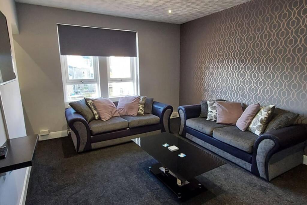 ein Wohnzimmer mit 2 Sofas und einem Tisch in der Unterkunft Zara Apartments in Dundee