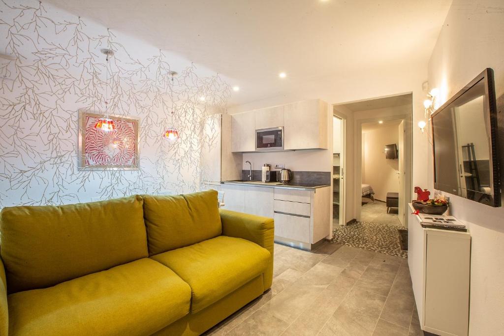 L'Atelier du Temps - Maison Maillet في أَويستا: غرفة معيشة مع أريكة صفراء ومطبخ