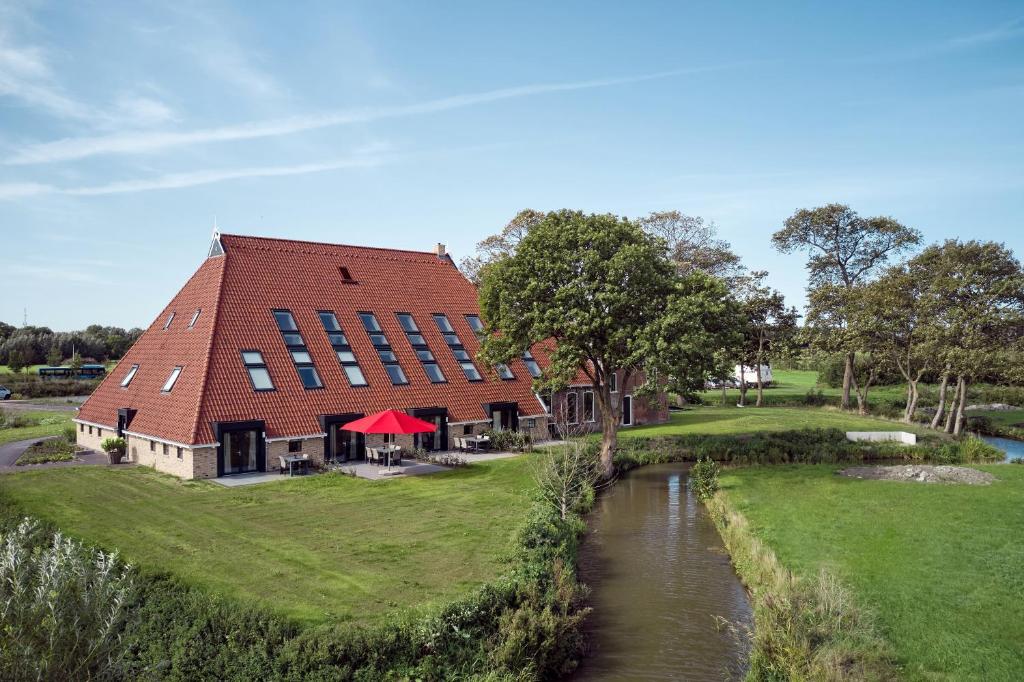 un edificio con techo rojo junto a un río en Farm house Van der Valk Hotel Leeuwarden, en Leeuwarden