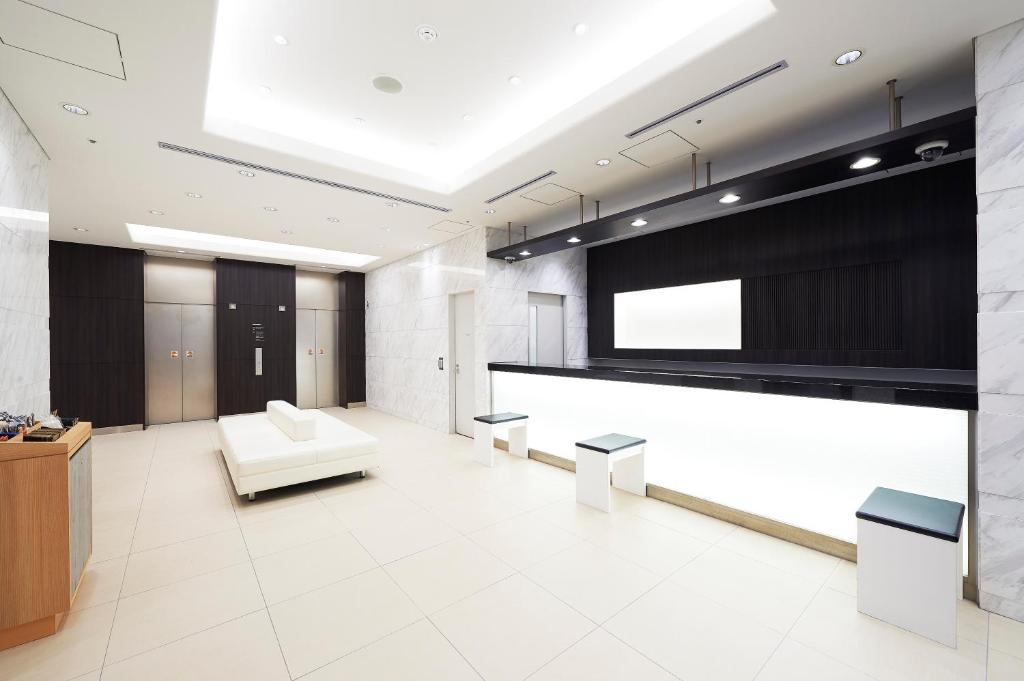 a lobby with a white couch and a large screen at Sotetsu Fresa Inn Kanda-Otemachi in Tokyo